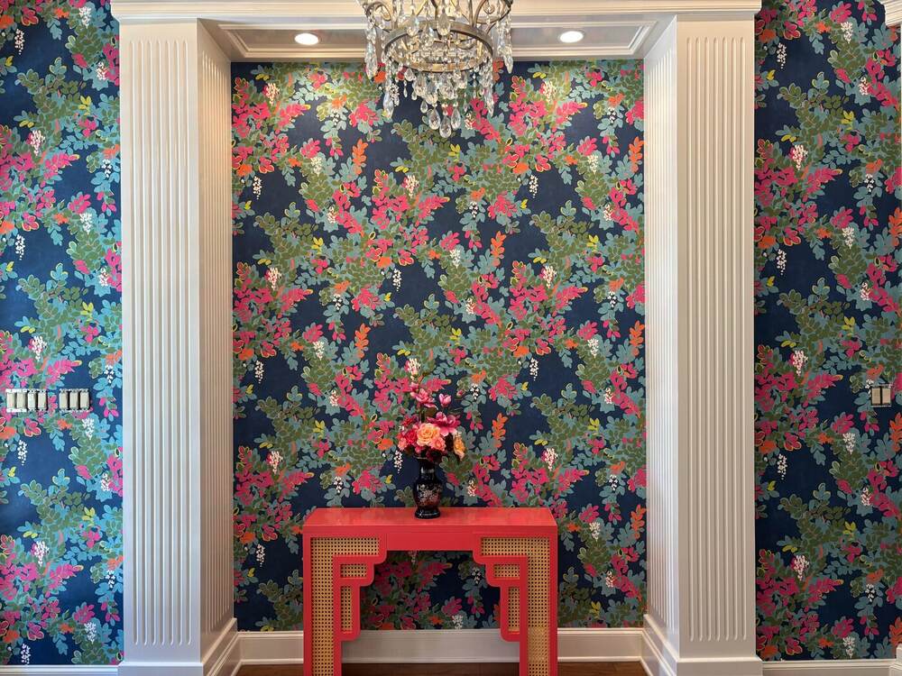 Warm floral wallpaper wrapping a residential entryway nook with a red console table in Temple, Texas